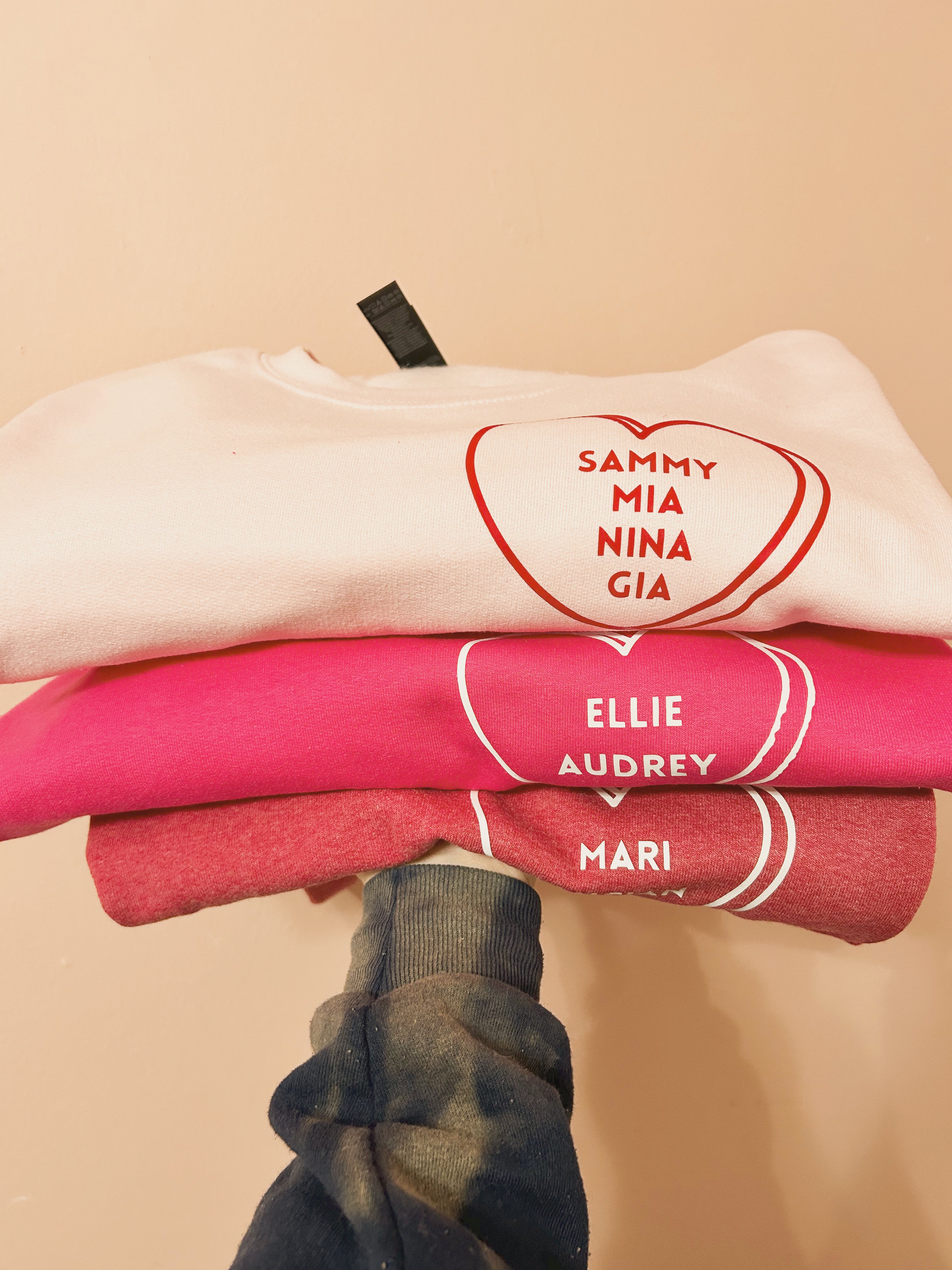 Stack of folded clothes with embroidered names on a beige background